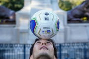Man balancing soccer ball on his head outdoors